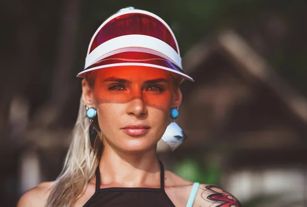 Portret van een mooi meisje in een rode visor close-up. Grote turquoise oorbellen dragen. Vakantie in Thailand — Stockfoto