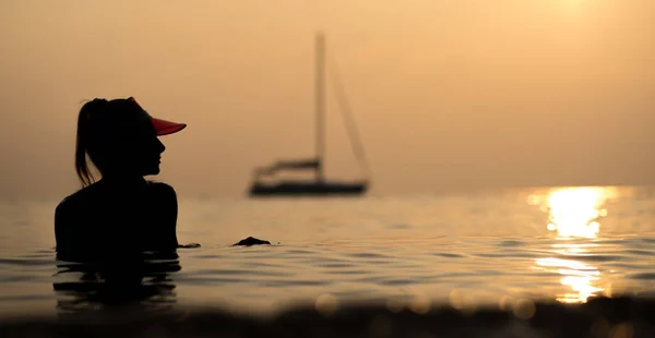 Silhouet van een mooi meisje Baden in de zee op haar jacht in de stralen van de ondergaande zon. Vakantie in Thailand — Stockfoto