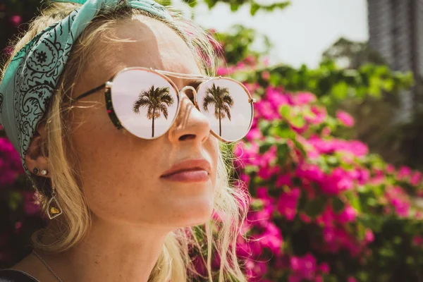 Retrato de close-up de uma jovem menina bonita em óculos com reflexo de palmas tropicais. Descanso. Turista moderno — Fotografia de Stock