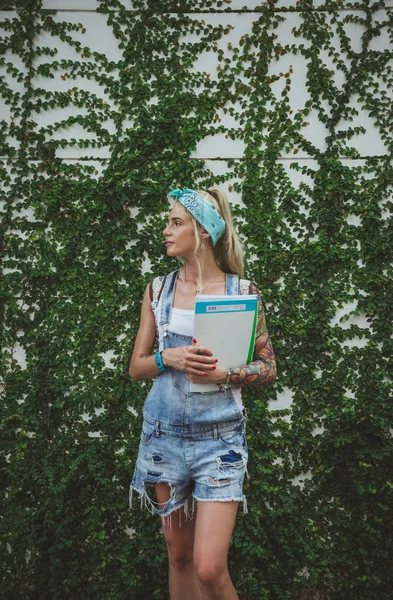 De student houdt vast aan de muur met groene planten klassen in de biologie te wachten. Moderne meisje. Model van tatoeages — Stockfoto