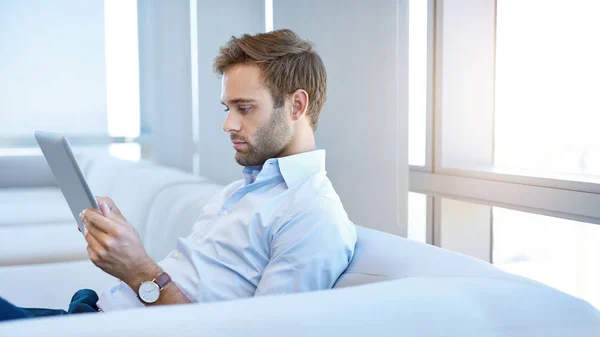 Stylish Young Man Sitting Modern Couch Seriously Reading Information Digital — Stock Fotó