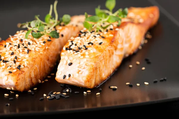 Grilled salmon on black plate — Stock Photo, Image