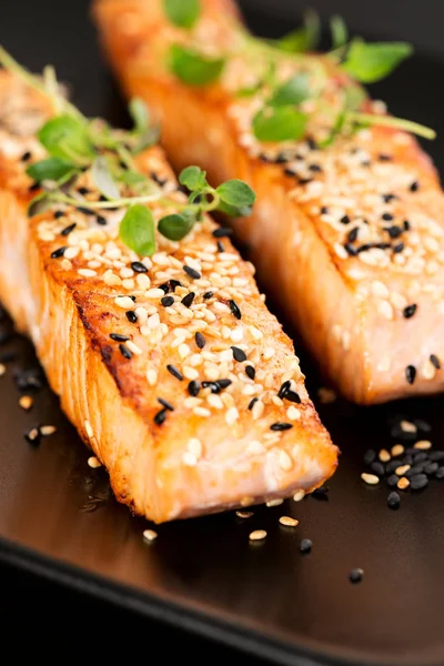 Grilled salmon on black plate — Stock Photo, Image
