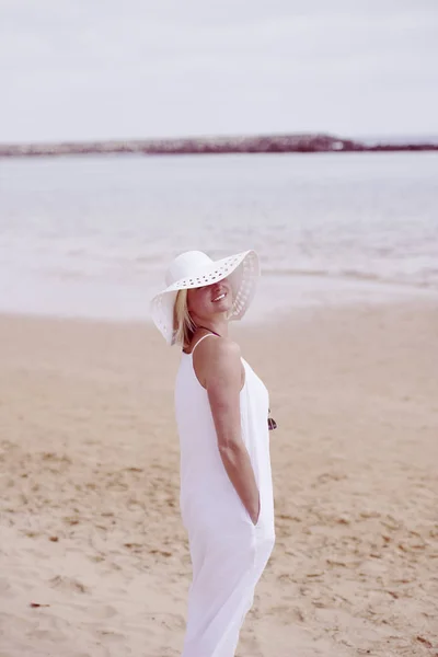 Mujer en la playa en vestido blanco y sombrero — Foto de Stock