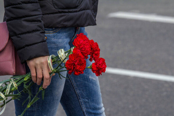 Red carnations in hand, as a symbol of remembrance.