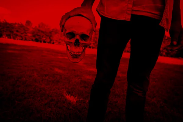 Släppa onda, Person med mänsklig skalle i hand, skrämmande bakgrund för halloween och bok täcka idéer — Stockfoto