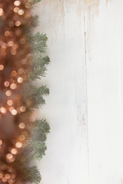 Hoja de Navidad con luces borrosas sobre fondo de madera — Foto de stock gratis