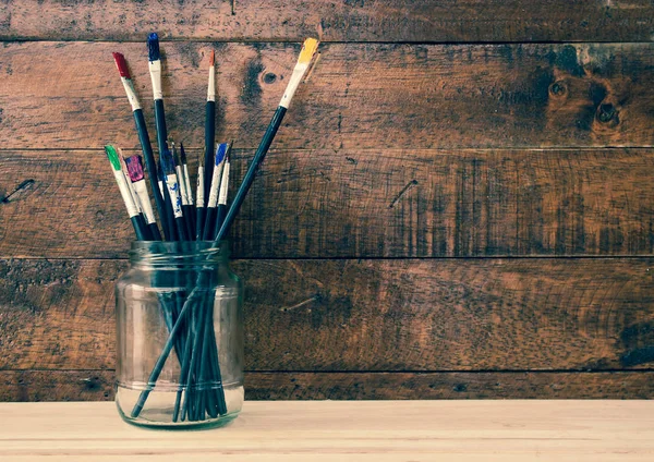 Used paint brush in jar with wooden background — Stock Photo, Image
