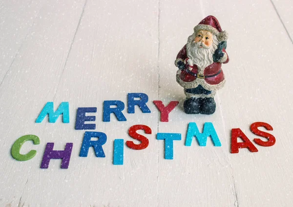 Enfeite de Natal com Papai Noel em fundo de madeira com texto Feliz Natal e neve — Fotografia de Stock