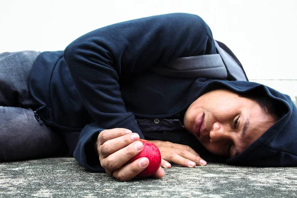 Hemlös person låg på golvet med ett äpple i handen — Stockfoto