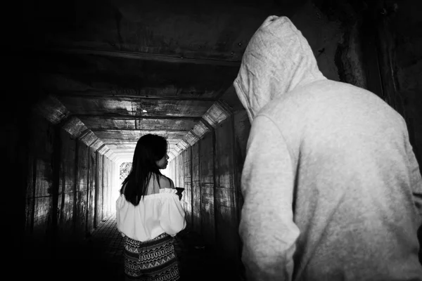 社会問題、トンネルで見知らぬ人に付きまとわれて歩きながら携帯電話で美しい女性 — ストック写真