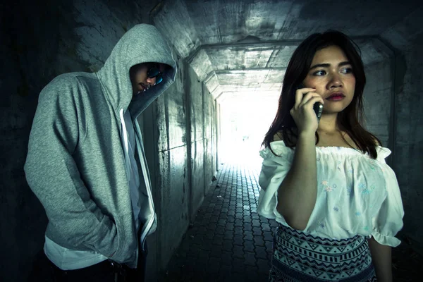 Social Issues,Beautiful woman on the phone while walking in the tunnel and being stalked by stranger — Stock Photo, Image