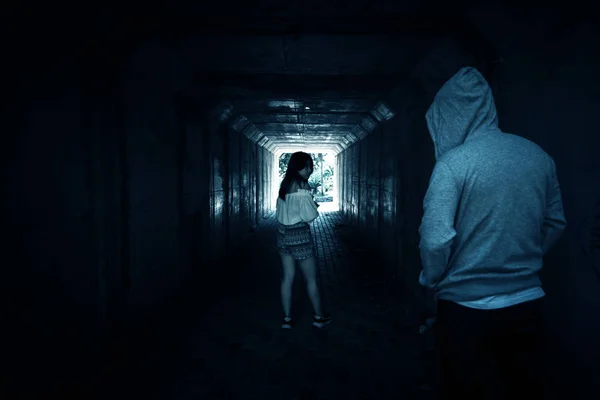 Sociale kwesties, mooie vrouw aan de telefoon tijdens het wandelen in de tunnel en gestalkt door vreemdeling — Stockfoto