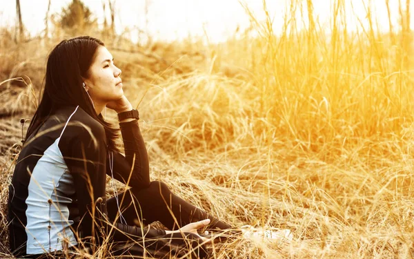 Mujer sentada en el campo de hierba disfrutar escuchando música — Foto de Stock
