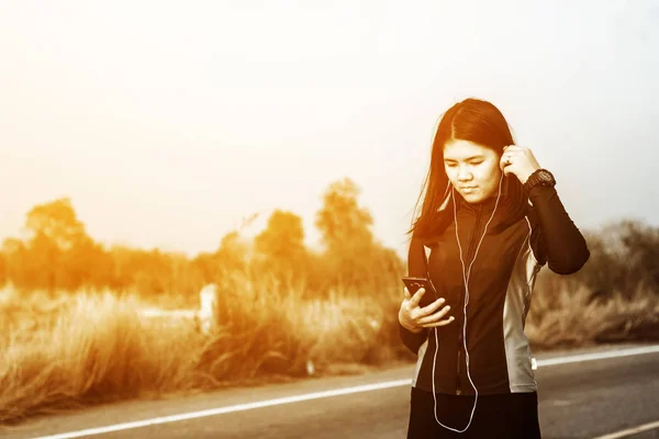 Woman in sportswear walking outdoor while listening music — Stock Photo, Image