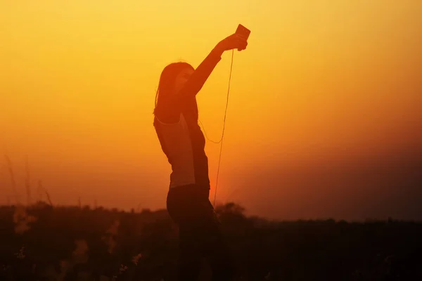 Silueta mujer tomando fotos de la puesta del sol mediante el uso de un teléfono inteligente — Foto de Stock