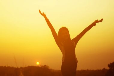 Mutlu kadın eller üzerinde gökyüzü günbatımı kaldırdı
