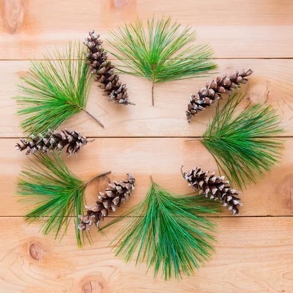 Dennenappels en takken in de vorm van de kroon van Kerstmis op houten t — Stockfoto