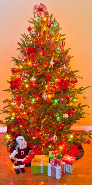 Gedecoreerde kerstboom omringd door giften verpakt presenteert een — Stockfoto