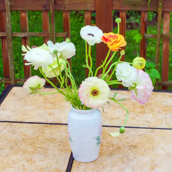 Ramo de flores de ranúnculo en la mesa de jardín . — Foto de Stock