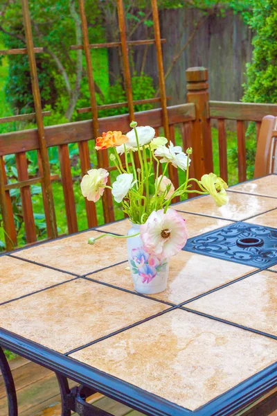 Boeket van ranunculus bloemen op tuinmeubelen. — Stockfoto
