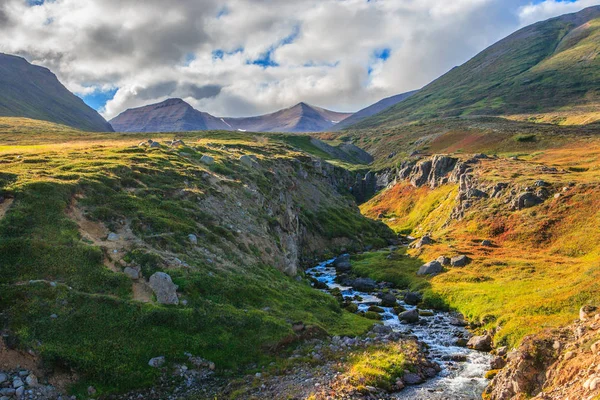 Wunderbare isländische Landschaft. Grasland, See, hohe bunte Berge und schöner Himmel. — Stockfoto