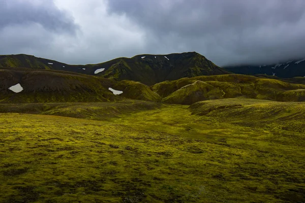 Wunderbare isländische Landschaft. Grasland, See, hohe bunte Berge und schöner Himmel — Stockfoto