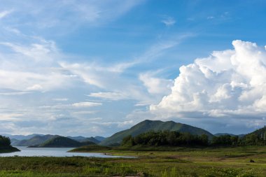 Mavi gökyüzü, yeşil dağ ve temiz su ile güzel bir sahne