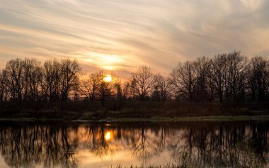 Nehrin üzerinde gün batımı, pembe gökyüzünün yansıması.