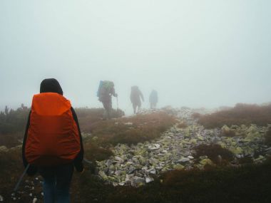 Turistler seyahat etmek sırt çantaları kayaları süt kalın sis içinde yürüyüş ile.