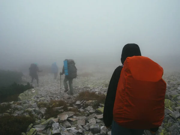 Turistler seyahat etmek sırt çantaları kayaları süt kalın sis içinde yürüyüş ile.