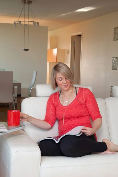 Mujer leyendo revista en sofá — Foto de Stock