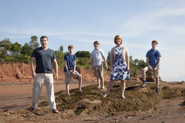 A family poses on a rock at the beach with attitude — Stock Photo, Image