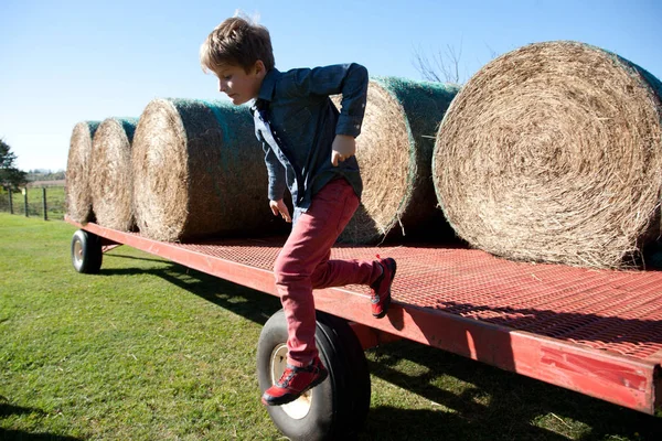 Boy jumping off tractor — Stock Photo, Image