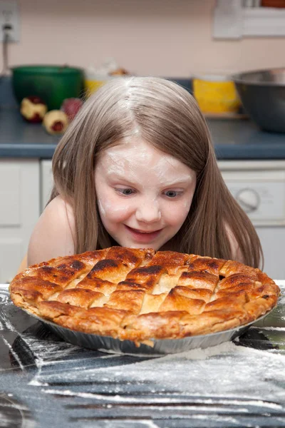 Chica mira al pastel horneado —  Fotos de Stock