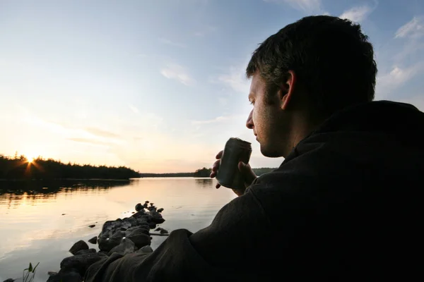 Человек с пивом на озере — стоковое фото