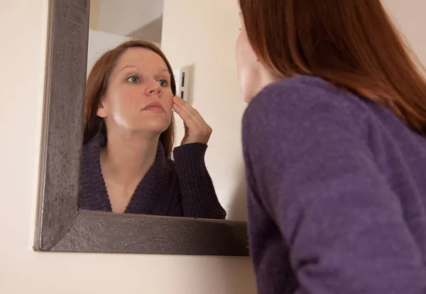 거울에 얼굴을 보고 하는 여자 — 스톡 사진