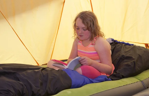 Little girl reading in tent — Stock Photo, Image