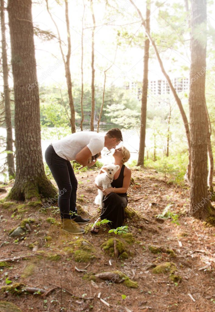 a soft glow in the woods while a couple kiss with pets 