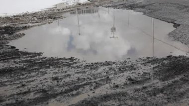 gökyüzü ve elektrik direği çamurlu su ile dolu dev bir çukur yansıtır 