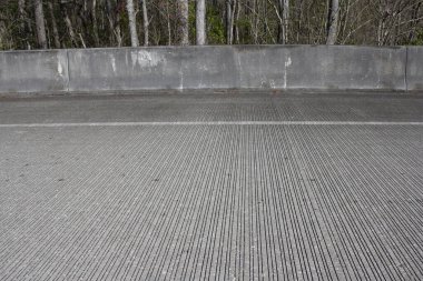 Otoyoldaki çimento bariyeri yolcuları araba kullanırken korur. 