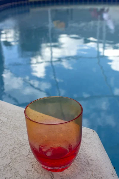 an empty pink glass or cup beside a swimming pool