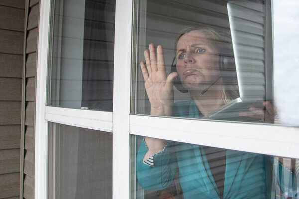 woman working with laptop and headset looking longingly outside 