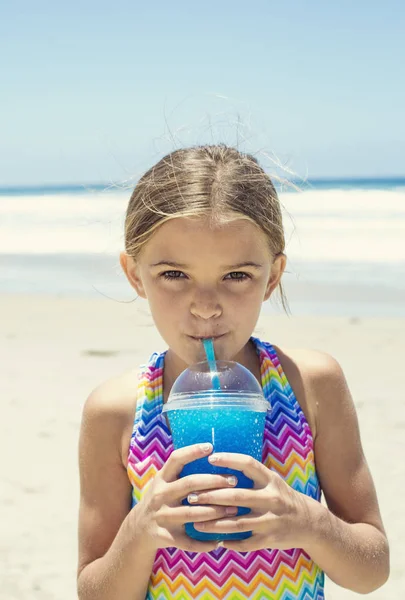 Ładna dziewczyna picia napój niebieski lód na plaży podczas letnich wakacji — Zdjęcie stockowe