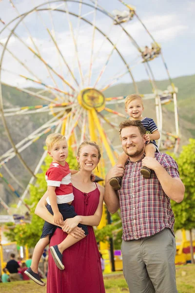 Cute young family enjoying a day at amusement park — Stock Photo, Image