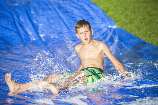 Teen boy sliding down a slip and slide outdoors