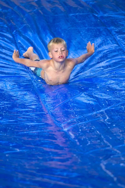Boy sliding down a slip and slide — Stock Photo, Image
