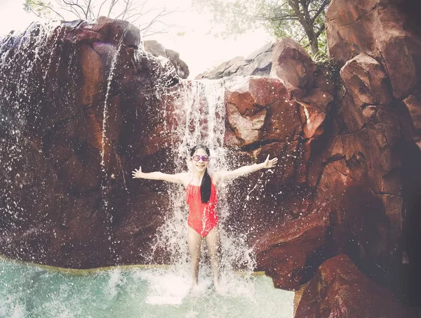 Chica joven jugando y salpicando en una cascada — Foto de Stock