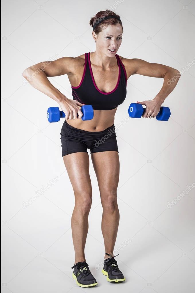 Strong Beautiful fitness woman lifting dumbbell weights