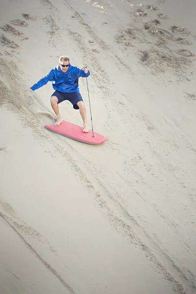 Man riding board down sand — Stock Photo, Image